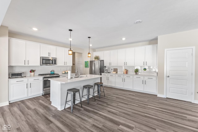 kitchen with appliances with stainless steel finishes, a kitchen island with sink, and white cabinets