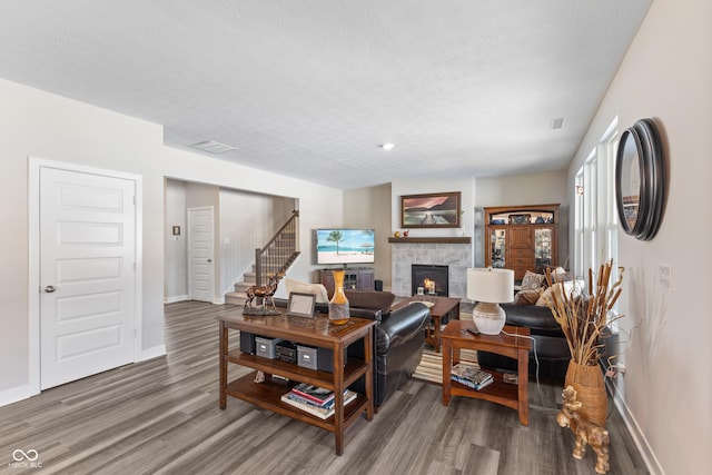 living room with hardwood / wood-style flooring, a fireplace, and a textured ceiling