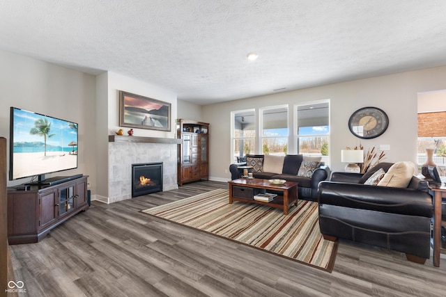 living room with a healthy amount of sunlight, a textured ceiling, a fireplace, and dark hardwood / wood-style flooring