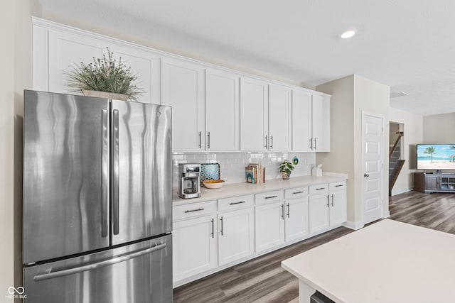 kitchen with white cabinets, stainless steel fridge, dark hardwood / wood-style flooring, and decorative backsplash