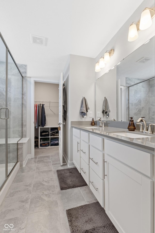 bathroom featuring a shower with door and vanity