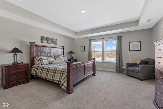 bedroom with light carpet and a raised ceiling