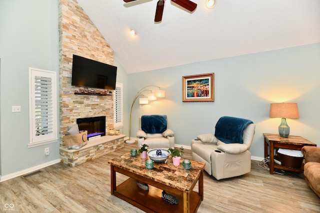 living room with ceiling fan, high vaulted ceiling, a fireplace, and light hardwood / wood-style floors