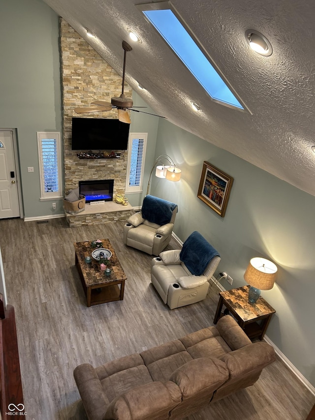 11710 E 75th St, Indianapolis, IN 46236 - living room with ceiling fan, hardwood / wood-style floors, vaulted ceiling with skylight, a fireplace, and a textured ceiling