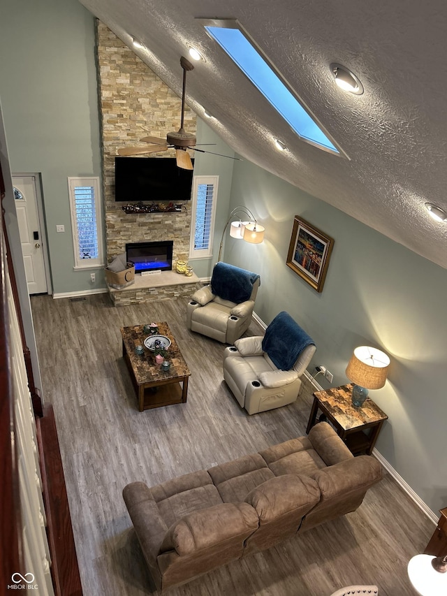11710 E 75th St, Indianapolis, IN 46236 - living room with hardwood / wood-style flooring, ceiling fan, lofted ceiling with skylight, a fireplace, and a textured ceiling