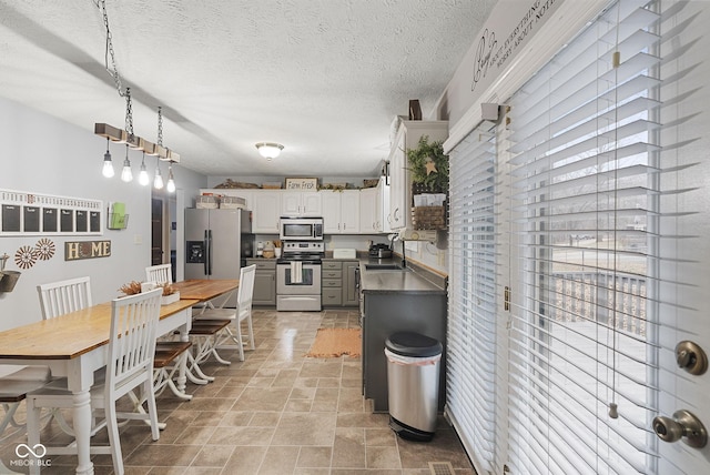 kitchen with sink, white cabinetry, a textured ceiling, pendant lighting, and stainless steel appliances