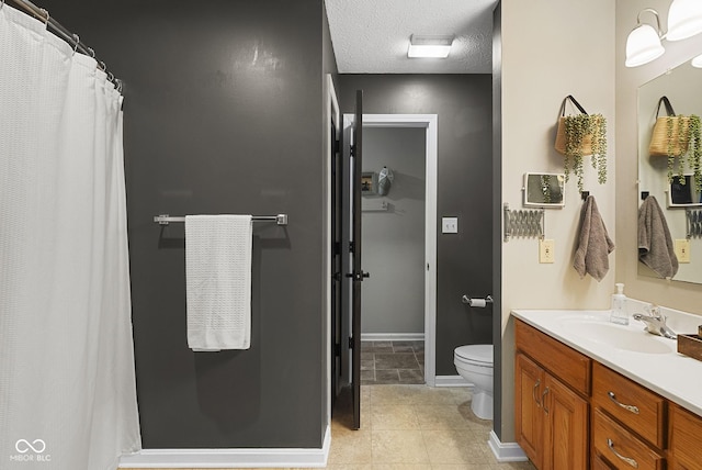 bathroom with tile patterned floors, vanity, toilet, and a textured ceiling