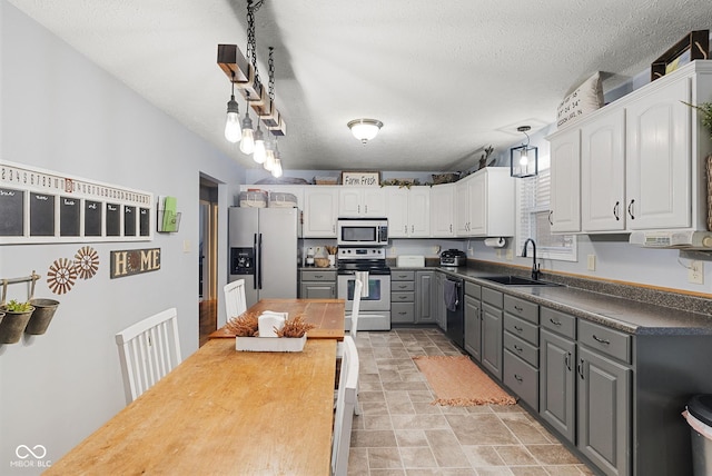 kitchen with sink, gray cabinets, appliances with stainless steel finishes, white cabinetry, and decorative light fixtures