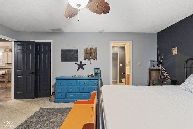 bedroom with ceiling fan, ensuite bath, and light carpet