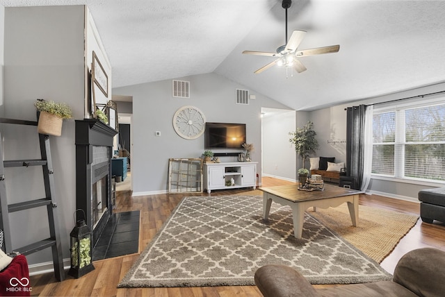 living room with lofted ceiling, hardwood / wood-style floors, a textured ceiling, and ceiling fan