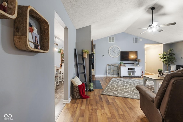 living room with ceiling fan, lofted ceiling, hardwood / wood-style floors, and a textured ceiling