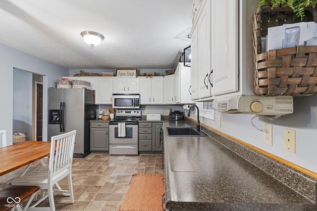 kitchen with sink, appliances with stainless steel finishes, gray cabinetry, a textured ceiling, and white cabinets