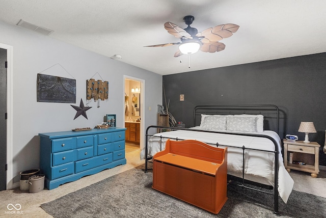 bedroom with ensuite bathroom, light colored carpet, ceiling fan, and a textured ceiling