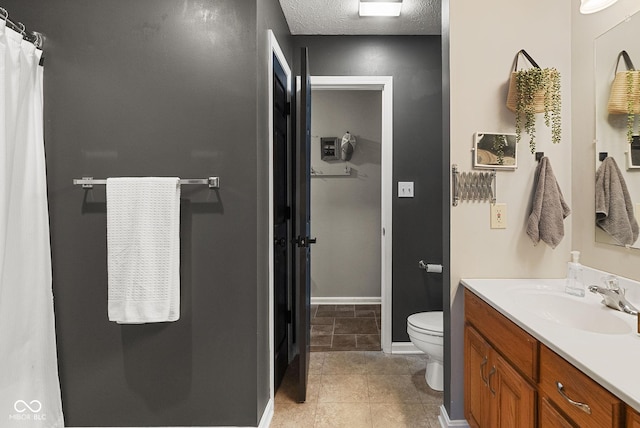 bathroom with vanity, toilet, tile patterned flooring, and a textured ceiling