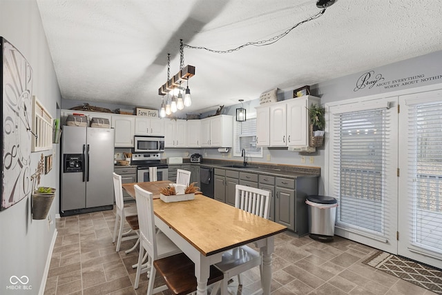 kitchen with sink, gray cabinetry, white cabinetry, stainless steel appliances, and decorative light fixtures