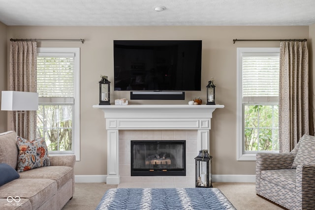 carpeted living room featuring a tiled fireplace and a textured ceiling