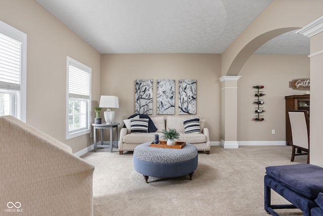 carpeted living room with a textured ceiling and ornate columns