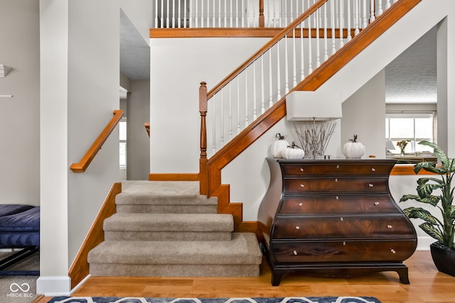 stairway with wood-type flooring and a high ceiling