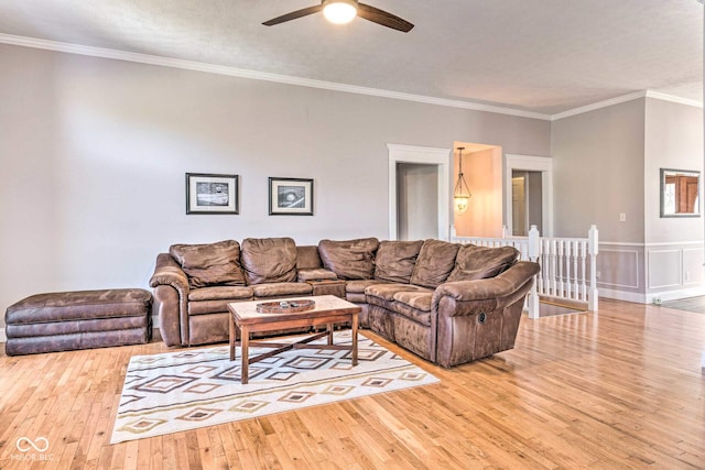 living area with wood-type flooring, ornamental molding, and a ceiling fan