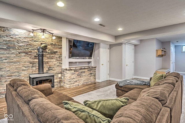 living room with visible vents, wood finished floors, a wood stove, and baseboards