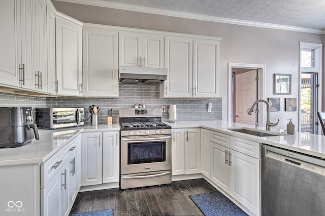 kitchen with dark wood finished floors, stainless steel appliances, under cabinet range hood, white cabinetry, and a sink