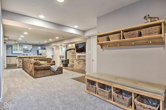 living area featuring carpet flooring, a wood stove, and recessed lighting