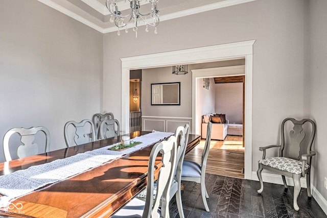 dining room featuring crown molding, dark wood-type flooring, a notable chandelier, and baseboards