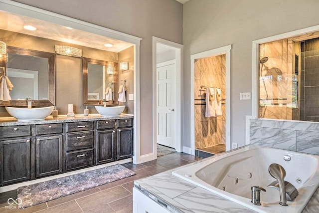 bathroom with wood finish floors, double vanity, a sink, a whirlpool tub, and baseboards