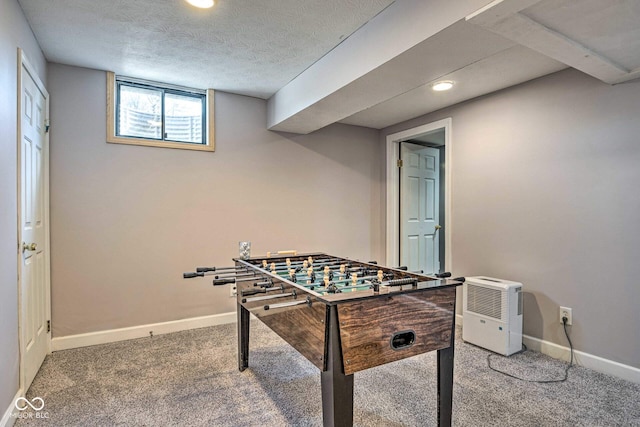 recreation room with carpet floors, a textured ceiling, and baseboards