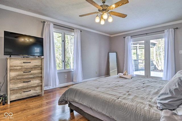 bedroom featuring ornamental molding, access to outside, visible vents, and wood finished floors