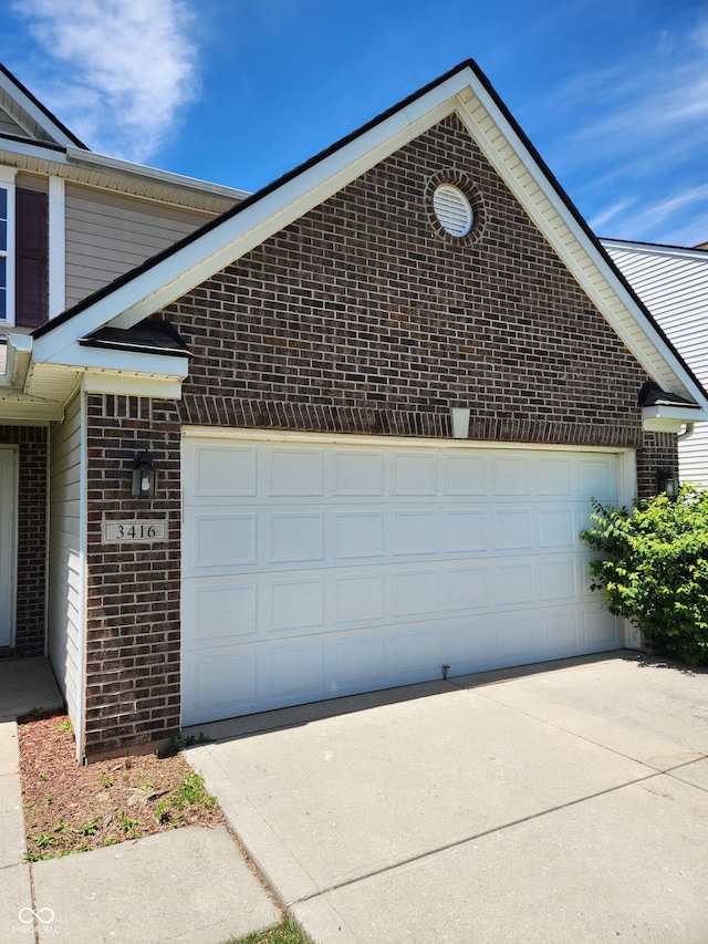 view of side of home with brick siding, concrete driveway, and an attached garage