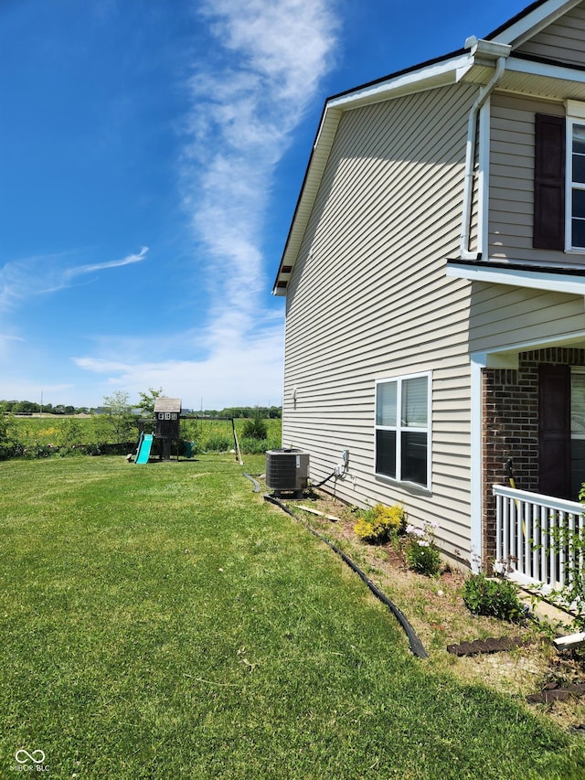 view of home's exterior featuring cooling unit, brick siding, a lawn, and a playground
