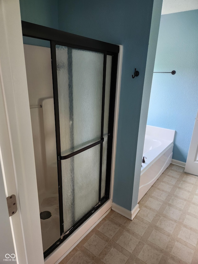 full bath featuring a stall shower, baseboards, and a garden tub