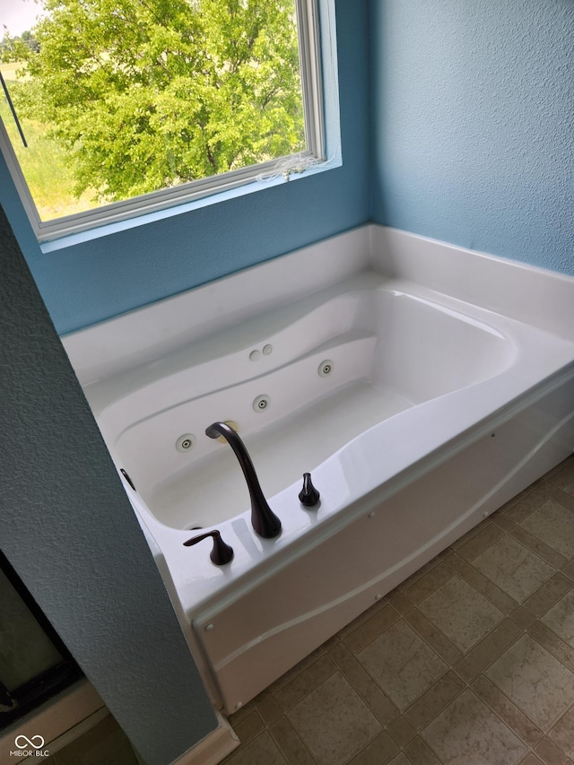 full bathroom with a tub with jets and a textured wall
