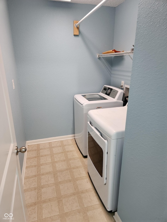 washroom featuring washer and clothes dryer, light floors, and baseboards