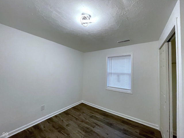 unfurnished room with dark wood-type flooring and a textured ceiling