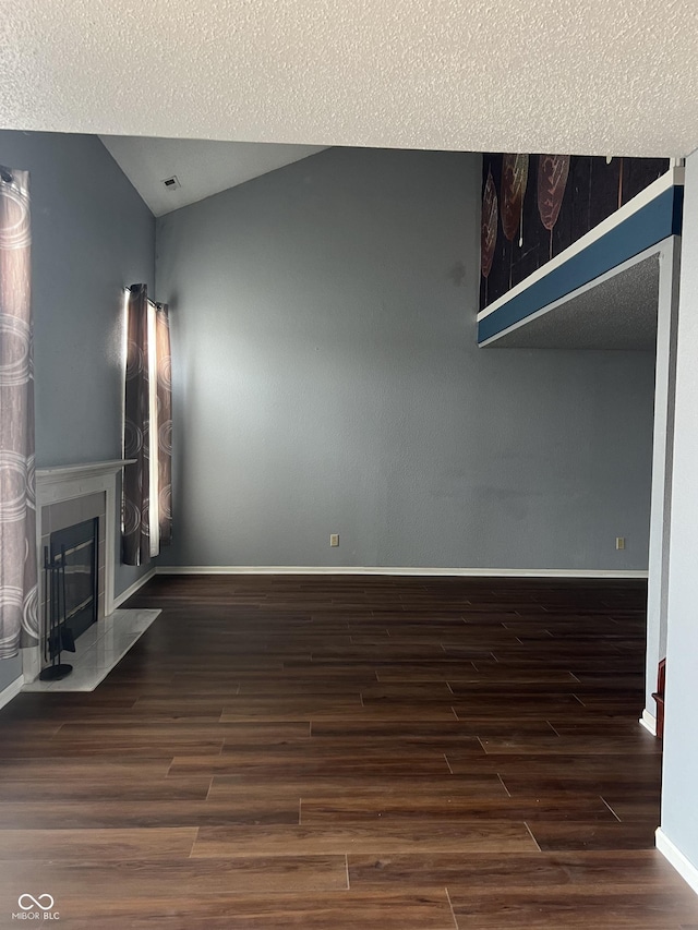 unfurnished living room featuring dark hardwood / wood-style flooring, vaulted ceiling, and a textured ceiling