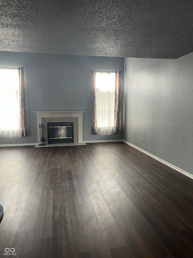 unfurnished living room with a fireplace, dark hardwood / wood-style flooring, and a textured ceiling