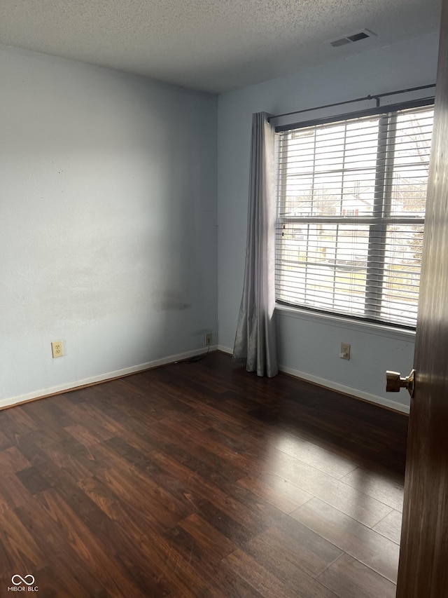 empty room featuring a textured ceiling and dark hardwood / wood-style flooring