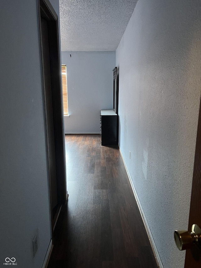 hallway with dark hardwood / wood-style floors and a textured ceiling