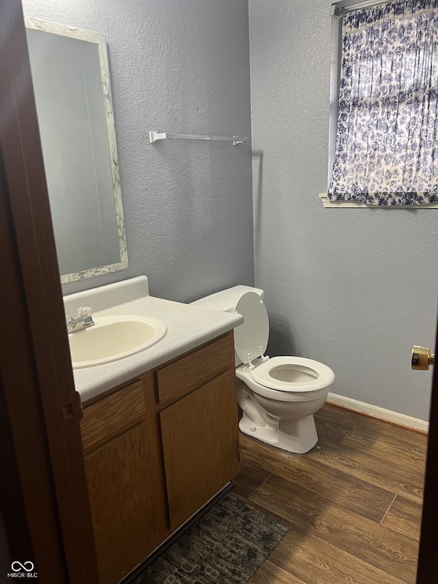 bathroom with wood-type flooring, vanity, and toilet