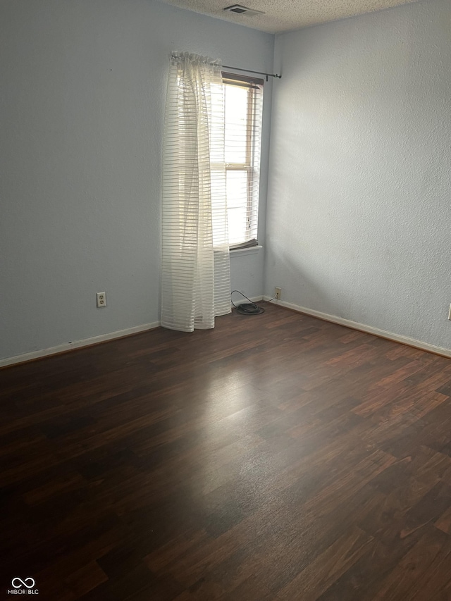 spare room with dark hardwood / wood-style flooring and a textured ceiling