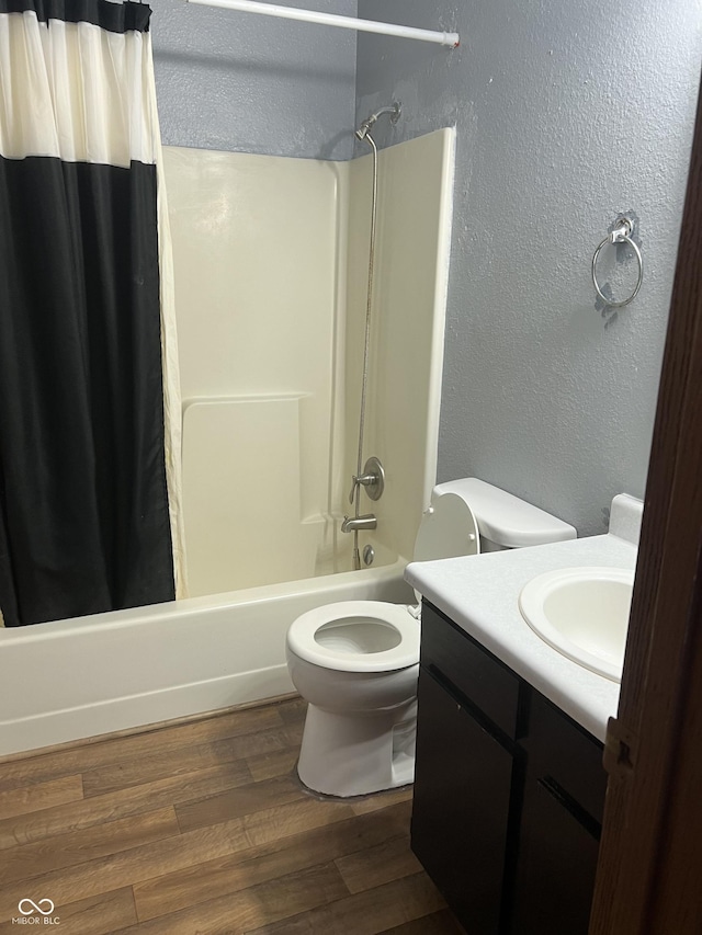 full bathroom featuring wood-type flooring, toilet, shower / bath combo with shower curtain, and vanity