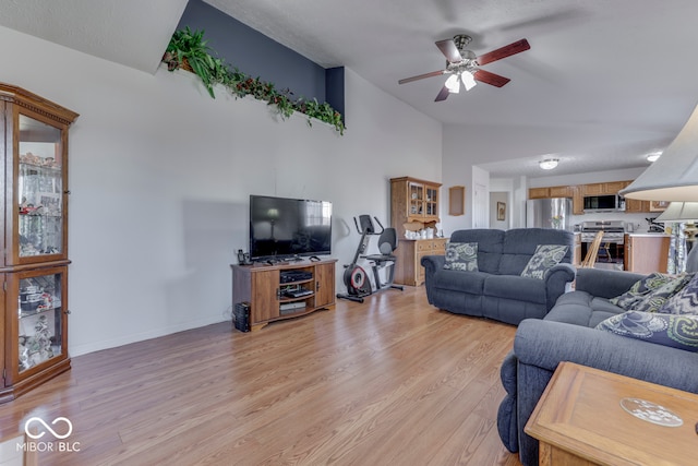 living room featuring vaulted ceiling, ceiling fan, and light hardwood / wood-style flooring