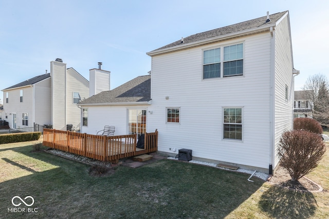 rear view of house featuring a wooden deck and a lawn