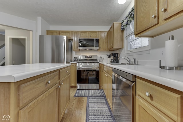 kitchen featuring stainless steel appliances, light hardwood / wood-style floors, sink, and a textured ceiling