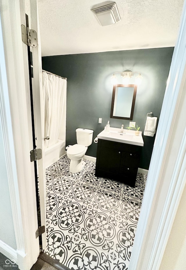 full bathroom featuring shower / tub combo with curtain, toilet, a textured ceiling, vanity, and tile patterned flooring