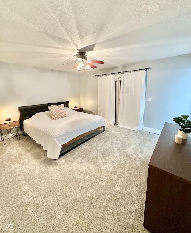 carpeted bedroom featuring ceiling fan and a textured ceiling