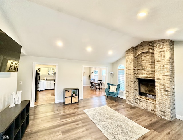 living room featuring a fireplace, vaulted ceiling, and light hardwood / wood-style floors