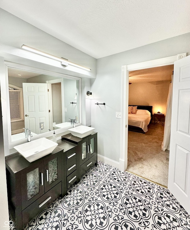 bathroom featuring tile patterned floors, vanity, vaulted ceiling, and a textured ceiling